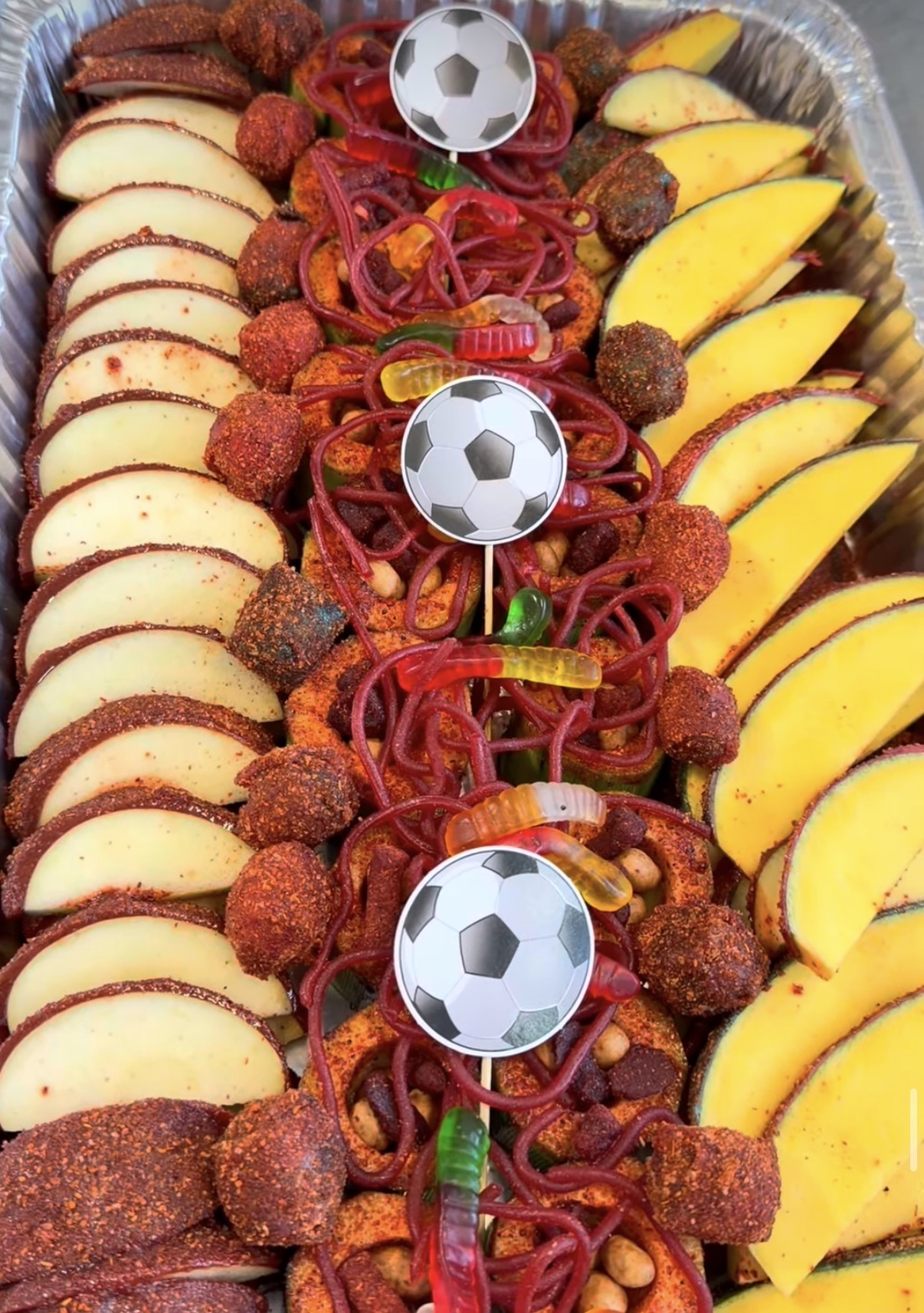 Charola de botanas preparadas con manzana enchilada, mango, tamarindo y dulces gomitas