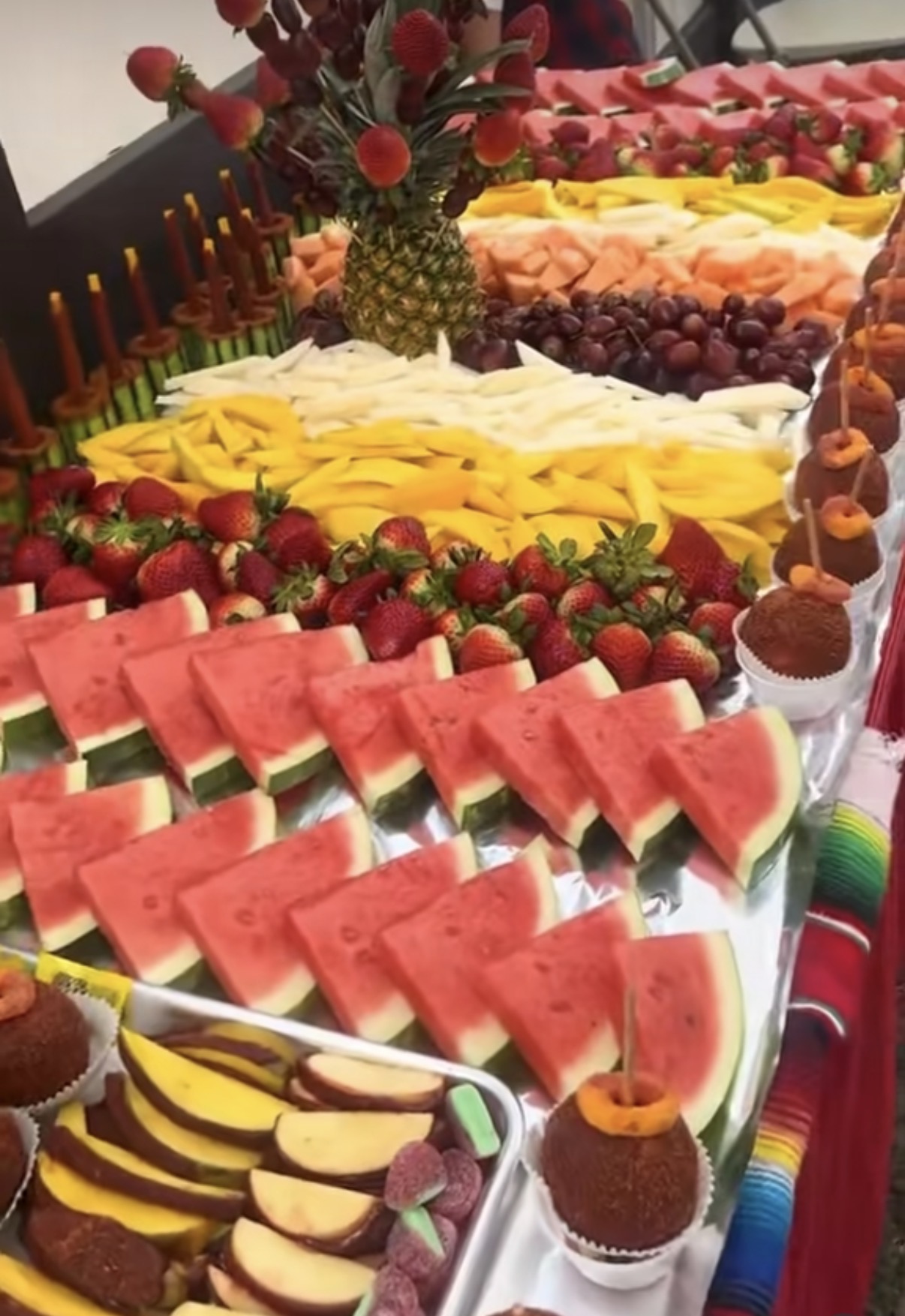 Mesa de fruta para evento con sandía, mango, melón, uvas, fresas y manzanas enchiladas